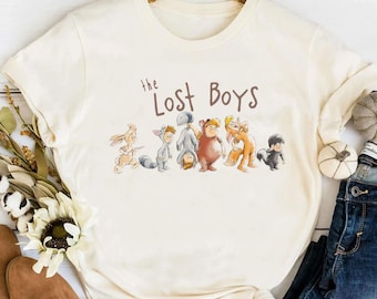 May include: A white t-shirt with a brown graphic of the Lost Boys from the movie Hook. The graphic features the characters in a line, with the text "the Lost Boys" above them.
