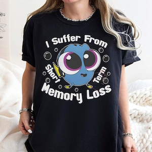 May include: Black t-shirt featuring a cartoon blue fish with large eyes and the text "I Suffer From Short Term Memory Loss." The design includes bubbles around the fish. The shirt is a casual wear item.