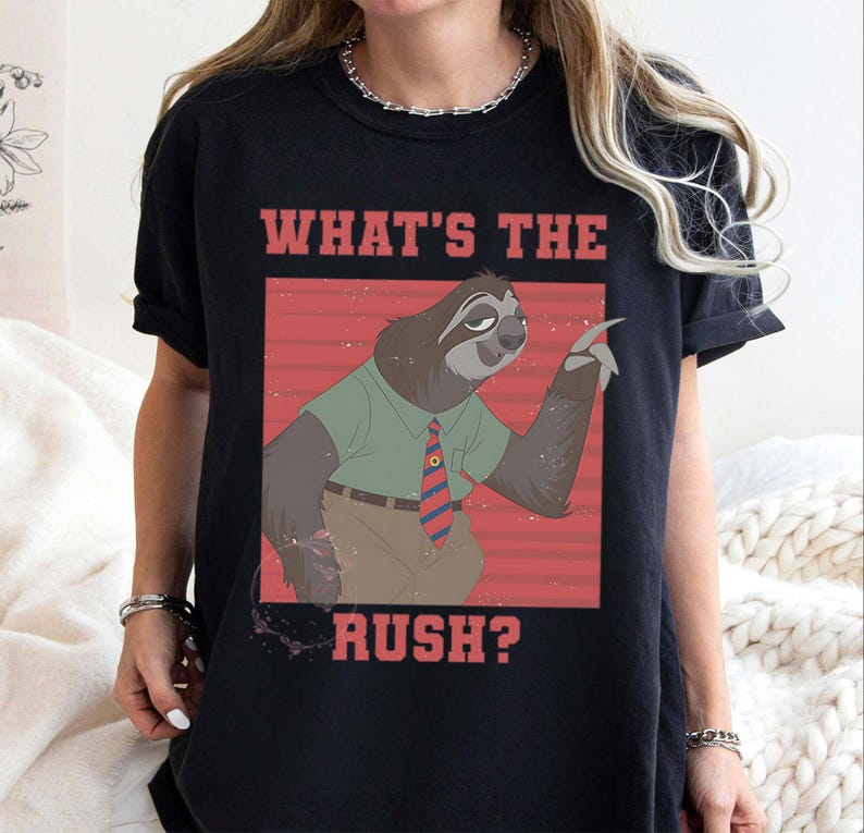 May include: Black t-shirt featuring a cartoon sloth character in a green shirt and striped tie, with the text "WHAT'S THE RUSH?" in red letters. The sloth is gesturing with its hand against a red background.
