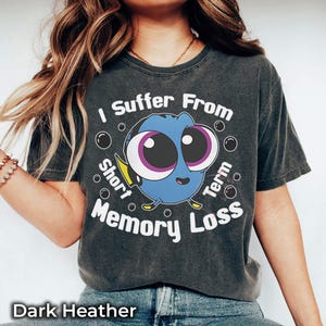 May include: Dark heather gray t-shirt featuring a cartoon Dory character with the text "I Suffer From Short Term Memory Loss." The design includes bubbles around the character. The shirt is a comfortable, casual wear.
