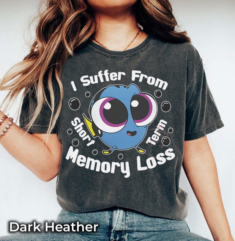 May include: Dark heather gray t-shirt featuring a cartoon Dory character with the text "I Suffer From Short Term Memory Loss." The design includes bubbles around the character. The shirt is a comfortable, casual wear.