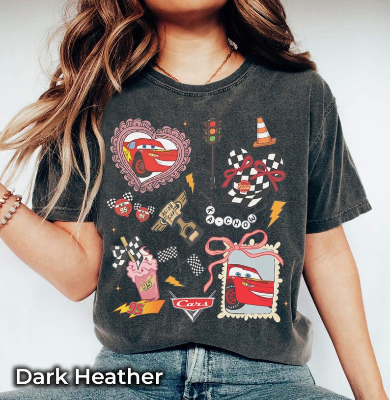 May include: Dark heather t-shirt featuring a Cars-themed graphic. The design includes Lightning McQueen in a heart, checkered flags, a traffic light, and the word "Cars". The shirt has a vintage, worn look.