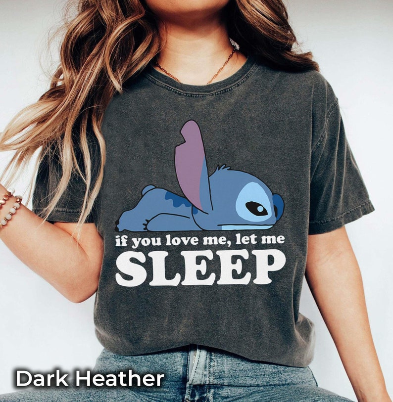 K&ouml;nnte beinhalten: Dunkelgraues T-Shirt mit einem blauen Stitch-Charakter aus Lilo & Stitch. Das Shirt tr&auml;gt den Text "if you love me, let me SLEEP" in Wei&szlig;.