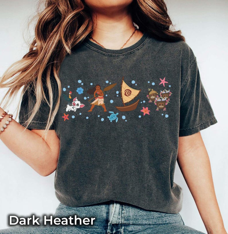 May include: Dark heather t-shirt with a vibrant graphic of animated characters, including a boat, a pig, and a turtle. The design is surrounded by stars and other elements. The text "Dark Heather" is printed at the bottom of the shirt.