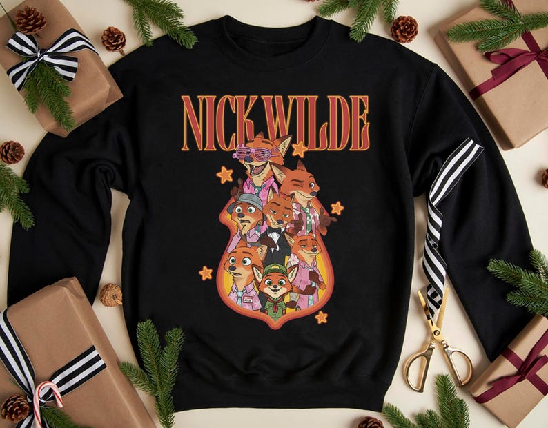 May include: Black crewneck sweatshirt featuring the text "NICK WILDE" in orange and red lettering. The sweatshirt has a graphic of several cartoon foxes in various outfits. The design is surrounded by orange stars.