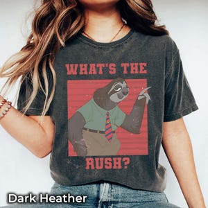 May include: Dark heather gray t-shirt featuring a cartoon sloth in a green shirt and tie, with the text "WHAT'S THE RUSH?" in red. The shirt has a vintage, worn look.