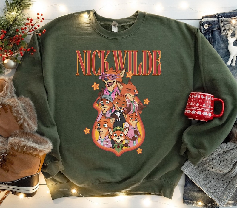 May include: Green sweatshirt featuring a graphic of Nick Wilde from Zootopia, with the text "NICK WILDE" in orange and red. The graphic includes multiple fox characters in various outfits. The sweatshirt is a crew neck style.
