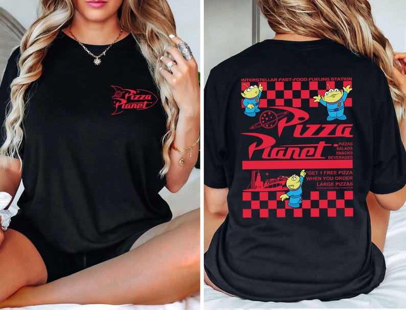 May include: Black t-shirt featuring the Pizza Planet logo in red on the front and back. The back design includes the text "INTERSTELLAR FAST-FOOD FUELING STATION" and cartoon aliens. The shirt also has the text "GET 1 FREE PIZZA WHEN YOU ORDER LARGE PIZZAS."