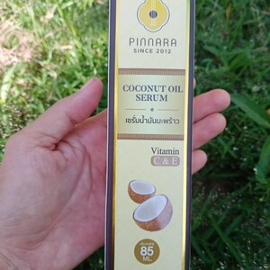 May include: A rectangular box of Pinnara Coconut Oil Serum. The box is primarily gold with brown accents and features the brand name and product details. The text includes "COCONUT OIL SERUM" and "Vitamin C & E". The box also shows a graphic of two coconut halves and contains 85 ML.