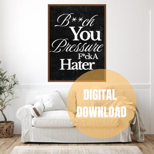 Könnte beinhalten: Gerahmter Wandkunstdruck mit dem Text "B**ch You Pressure F*ckA Hater" in weißer Schrift auf schwarzem Hintergrund. Der Druck wird über einem weißen Sofa angezeigt. Die Worte "DIGITAL DOWNLOAD" stehen in einem gelben Kreis.