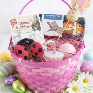 Peut inclure: Un panier de Pâques rose rempli de jouets pour chats, dont un poisson jouet, une souris et des coccinelles. Le panier contient également une fontaine à eau rose, des œufs de Pâques et une décoration en forme de lapin.