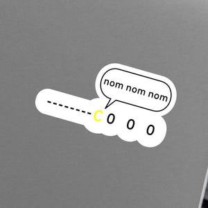 Può includere: Un adesivo bianco con una nuvoletta che dice "nom nom nom". L'adesivo ha una linea tratteggiata, una "C" gialla e tre piccoli cerchi. È posizionato su un laptop grigio.
