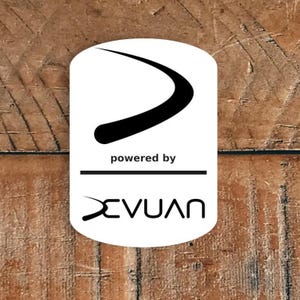 May include: White, rectangular sticker with a black curved design and the words "powered by" above the name "XEVUAN" in black. The sticker is on a wooden surface.