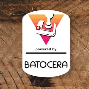 May include: White, oval-shaped logo with a retro game controller graphic, a pink triangle, and the text "powered by BATOCERA" on a wooden background. The controller has a red "B" on it.