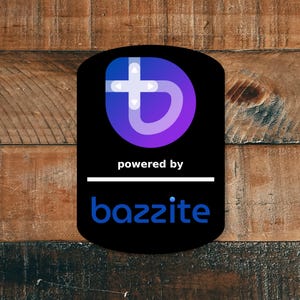 May include: A black, rounded rectangle logo with a stylized white plus sign inside a blue and purple shape. Below the shape is the text "powered by" above a white line, and the word "bazzite" in blue.