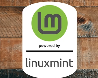 Può includere: Un adesivo bianco con un cerchio verde contenente un logo 'lm' stilizzato in grigio. Sotto il logo, il testo recita 'powered by' e 'linuxmint' in un font sans-serif. Lo sfondo è una superficie di legno.
