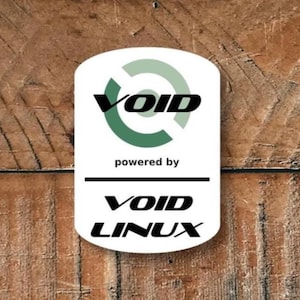 Può includere: Un adesivo bianco con la scritta "VOID" in nero, racchiusa in un design verde, e "powered by" sotto. La sezione inferiore recita "VOID LINUX". L'adesivo è posto su uno sfondo di legno.