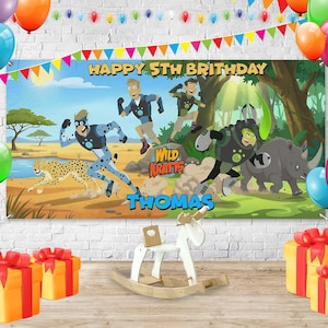 May include: A birthday banner with the text "Happy 5th Birthday Thomas" featuring cartoon characters and a cheetah. The banner is decorated with balloons and colorful bunting. There are wrapped gifts and a rocking horse in front of the banner.