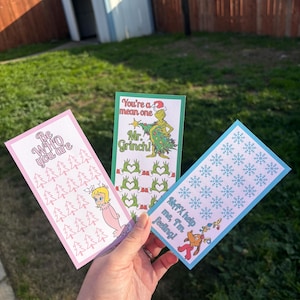 May include: Three colorful bookmarks with Dr. Seuss characters. One pink bookmark says "Be WHO you are" with a cartoon character and trees. The green bookmark says "You're a mean one Mr. Grinch!" The blue bookmark says "MAX help me, I'm feeling!"