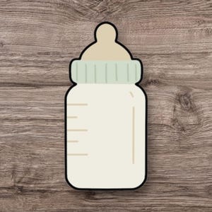 May include: A cartoon-style baby bottle illustration with a black outline. The bottle is filled with a creamy liquid and has a light green cap and a beige nipple. Measurement lines are visible on the side. The background is a wooden surface.
