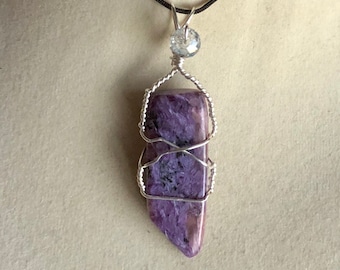 May include: A purple and silver wire-wrapped pendant featuring a natural stone with a crystal accent.