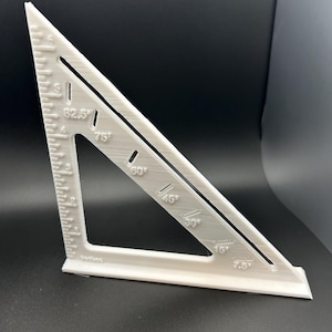 Puede incluir: Una escuadra de velocidad blanca, una herramienta triangular con medidas en pulgadas y ángulos en grados. Tiene marcas para ángulos de 7,5, 15, 30, 45, 60, 75 y 90 grados, y medidas en pulgadas.