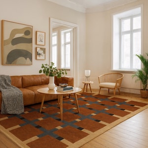 Pode incluir: Uma sala de estar com um sofá de couro castanho, uma mesa de centro redonda de madeira e um tapete estampado. O tapete apresenta um design geométrico em tons de castanho, azul e bege. Obras de arte adornam a parede e uma cadeira pequena está perto de uma janela.
