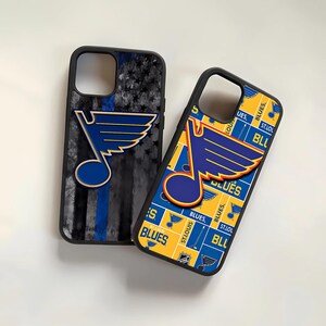 May include: Two phone cases featuring the St. Louis Blues hockey team logo. One case has a blue, yellow, and white pattern with the team's logo in the center. The other case has a black and blue American flag design with the team's logo in the upper right corner.