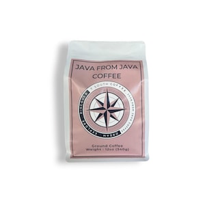 May include: A white coffee bag with a dusty pink label featuring the text JAVA FROM JAVA COFFEE and a compass rose graphic. The label includes the words DISCOVER, EXPLORE, DREAM, and 7 SOUTH COFFEE. It states Ground Coffee and Weight: 12oz (340g).