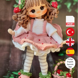 May include: A handmade crochet doll wearing a pink dress with strawberry accents, a matching hat, and striped stockings. The doll has brown curly hair and is holding a basket. The image includes the text "PDF PATTERN ONLY - NOT FINISHED DOLL."