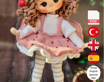 Puede incluir: Muñeca de ganchillo hecha a mano con un vestido rosa con detalles de fresas, un sombrero a juego y medias a rayas. La muñeca tiene el pelo rizado castaño y sostiene una cesta. El texto "PDF PATTERN ONLY - NOT FINISHED DOLL" está incluido.