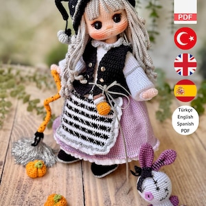 May include: A crochet doll pattern featuring a doll with long grey hair, a black hat, a white blouse, a black waistcoat, and a lavender skirt. The doll holds a broom with an orange handle and silver bristles. A small white voodoo-style doll and two orange pumpkins are included.