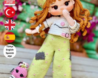 May include: A crochet doll with red hair, wearing a green hat and trousers with pink spots. The doll has a white shirt and a small pink accessory. The text "PDF PATTERN ONLY - NOT FINISHED DOLL" is at the bottom.