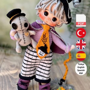 May include: A crochet doll with gray hair, wearing a purple shirt, black and white striped pants, and a black hat, holding a small gray voodoo-style doll. An orange tie with a spiderweb and skull design is worn. Text reads: PDF PATTERN ONLY – NOT FINISHED DOLL.