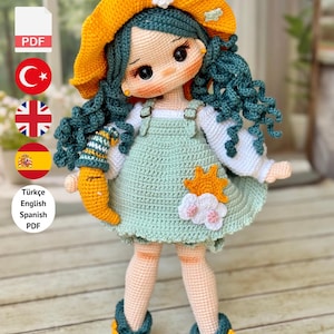 May include: A handmade crochet doll with teal hair and a yellow hat. The doll wears a mint green dress with white sleeves and a flower and sun applique. The text on the image says "PDF PATTERN ONLY - NOT FINISHED DOLL."