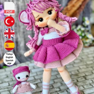 May include: A handmade crochet doll with pink hair, a matching dress, and cat ears. The doll has a smaller version next to it. The image includes flags and text that says "PDF Pattern Only - Not Finished Doll."
