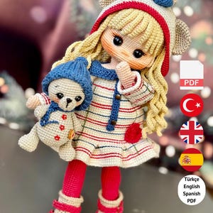 Może przedstawiać: Ręcznie robiona szydełkowa lalka z blond włosami, w paski i czapce z uszami misia. Lalka trzyma małego szydełkowego misia. Tekst "PDF PATTERN ONLY - NOT FINISHED DOLL" znajduje się na dole.