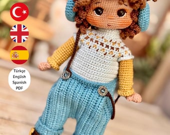 Könnte beinhalten: Gehäkelte Puppe mit blauem Kopfhörer, weißem und gelbem Pullover und blauer Hose. Die Puppe hat braune Haare und braune Schuhe. Der Text "PDF PATTERN ONLY - NOT FINISHED DOLL" befindet sich am unteren Rand des Bildes.