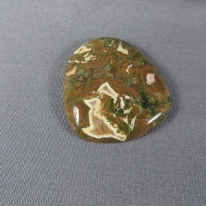 May include: A smooth, polished, green, brown, and white agate stone with a unique, swirling pattern.