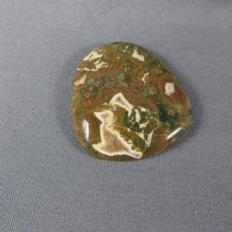 May include: A smooth, polished, green, brown, and white agate stone with a unique, swirling pattern.