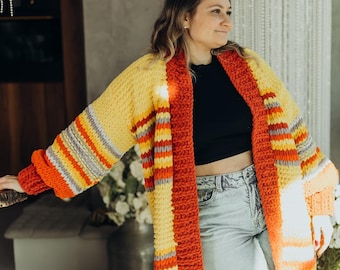 May include: A long, striped cardigan in yellow, orange, and red with a loose fit. The cardigan is crocheted and has a relaxed, casual style.
