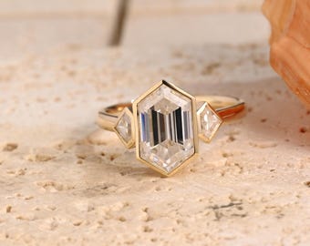 May include: A gold engagement ring with a large, clear, octagon-shaped center stone and two smaller, clear, triangular stones on either side.