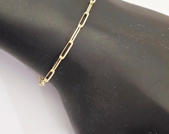 May include: A gold-toned bracelet featuring a series of elongated, rectangular links connected in a chain pattern. The metal links have a polished finish and are arranged in a repeating sequence to form a continuous, flexible band around the wrist.