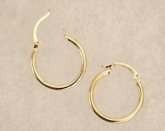 May include: A pair of gold hoop earrings. The earrings are simple and classic, with a smooth finish.