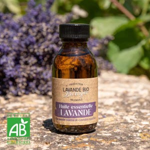 Puede incluir: Una botella de vidrio marrón de aceite esencial de lavanda con una tapa negra. La etiqueta dice "LAVANDE BIO Berenger" y "Huile essentielle LAVANDE". El fondo presenta flores de lavanda moradas y follaje verde.