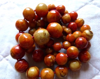 Könnte beinhalten: Eine Kette aus orangefarbenen und braunen Korallenperlen mit roter Schnur.
