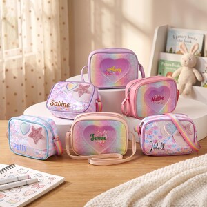 May include: Six rectangular crossbody bags in various pastel rainbow glitter finishes. Each bag features a clear heart-shaped window, a star-shaped patch, and a personalized name printed on the front. The bags have adjustable straps and zippers.