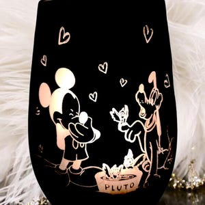 Könnte beinhalten: Schwarzer Glas-Kerzenhalter mit einer Silhouette von Mickey Mouse und Pluto mit Herzen und dem Wort "Pluto" am Boden.