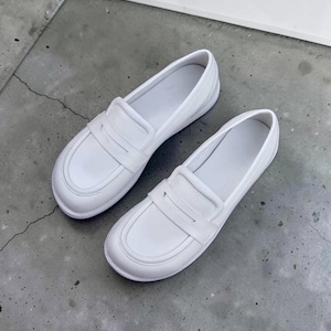 Puede incluir: Un par de mocasines blancos lisos sin cordones, con punta redondeada, una tira cl&aacute;sica con ranura sobre el empeine y un acabado liso y limpio. Estos zapatos tienen un dise&ntilde;o de perfil bajo con forro interior blanco y una suela resistente.