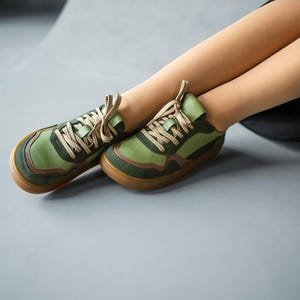 May include: Green and brown sneakers with tan laces. The shoes have a rounded toe and a brown sole. The sneakers are made of a combination of materials, including suede and leather. The shoes are designed for casual wear.